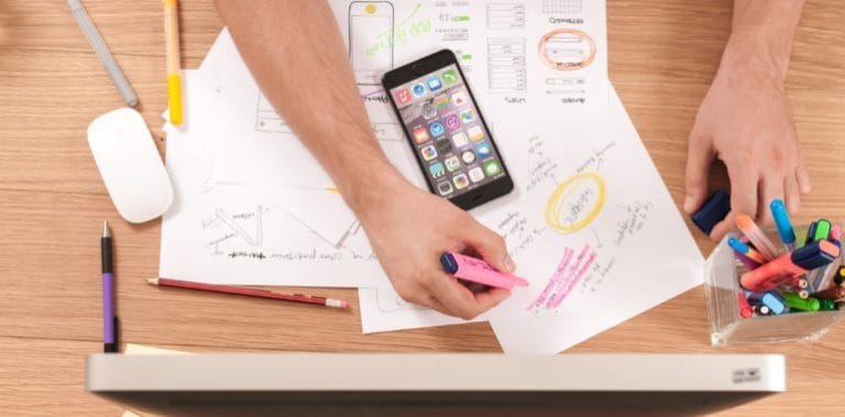 highlighting notes on a stack of papers with a smartphone nearby