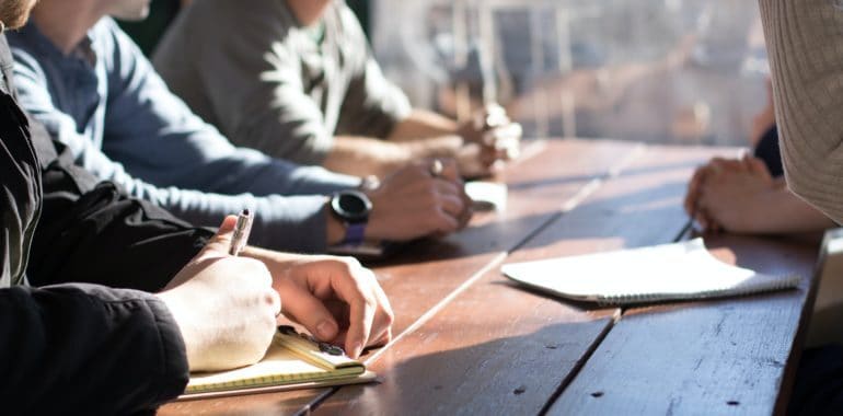 business people outside at a table taking notes