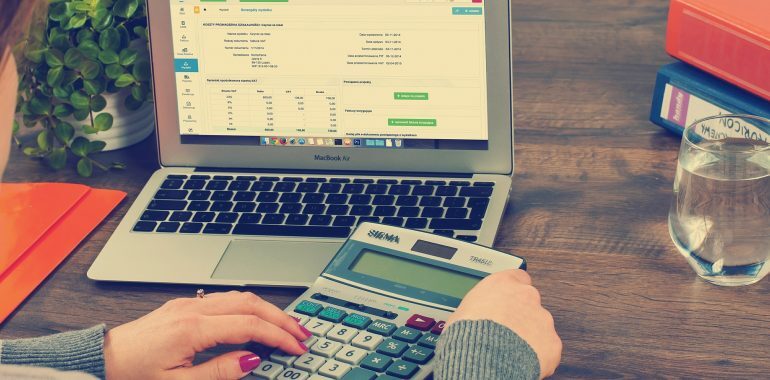person using a calculator right next to a laptop