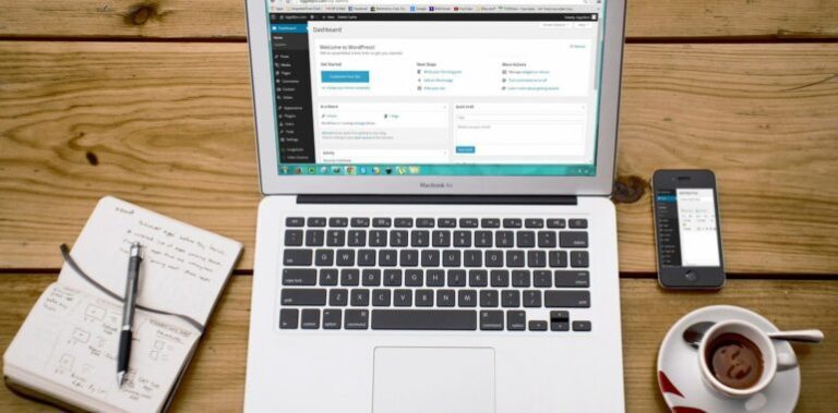 laptop on a desk near a coffee cup