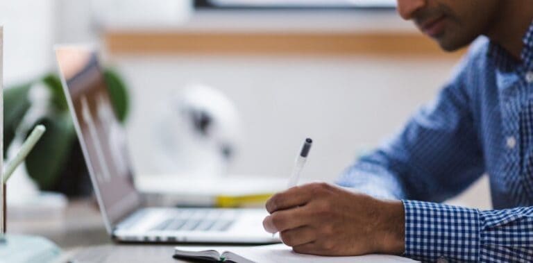 man taking notes from his laptop