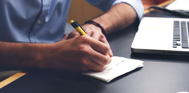 man writing on a notepad