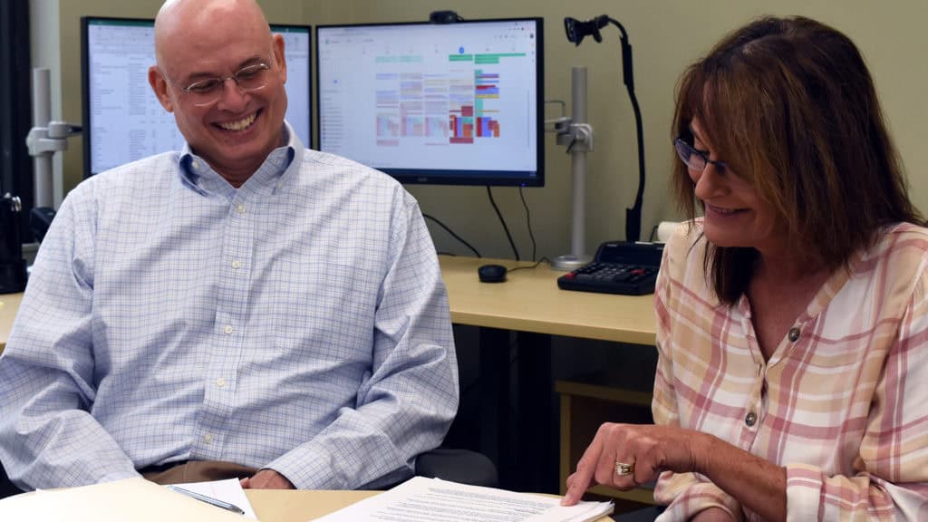 Two people discussing documents at table.