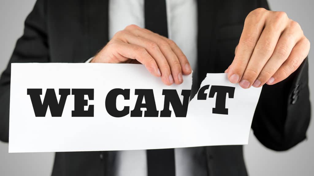 A person in a suit tearing a paper that says "WE CAN'T," separating the "T" to change the message to "WE CAN," symbolizing overcoming fear in entrepreneurship.